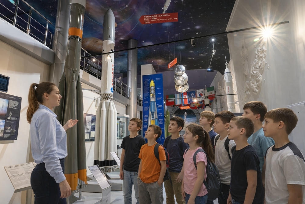 Группа школьников на экскурсии слушают рассказ про ракеты